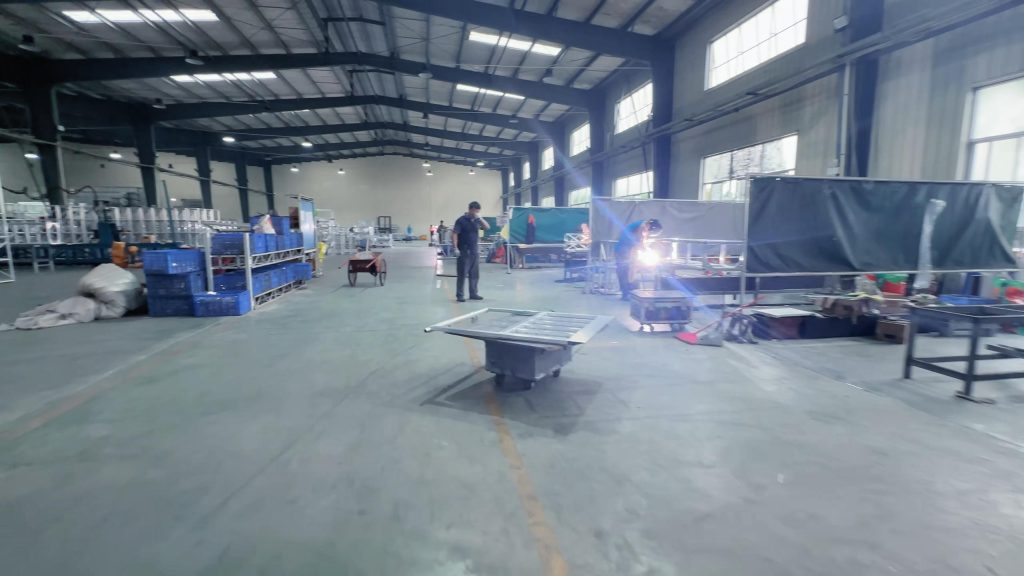 Aluminum truss welding line with workers assembling stage trusses for events