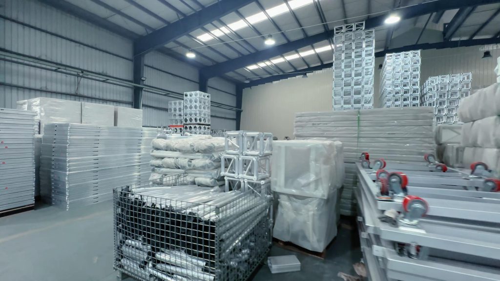 PE stretch film wrapping aluminum truss components in final packaging area after inspection and weld finishing