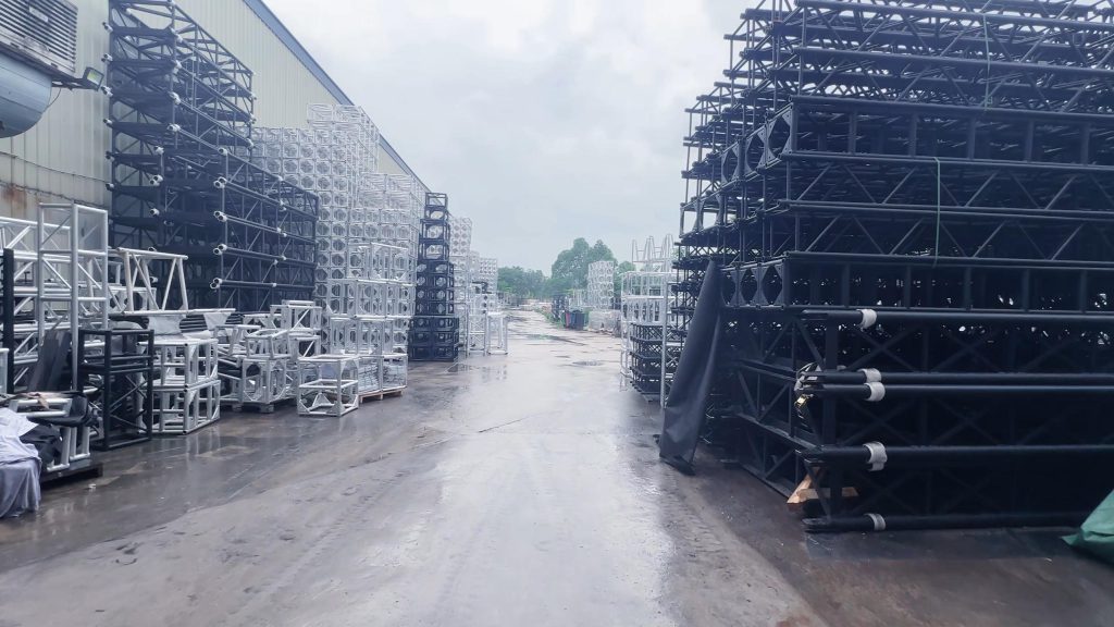 Outdoor storage yard with aluminum truss and heavy-duty steel truss systems for stage construction and electric cylinder lifting system truss equipment storage