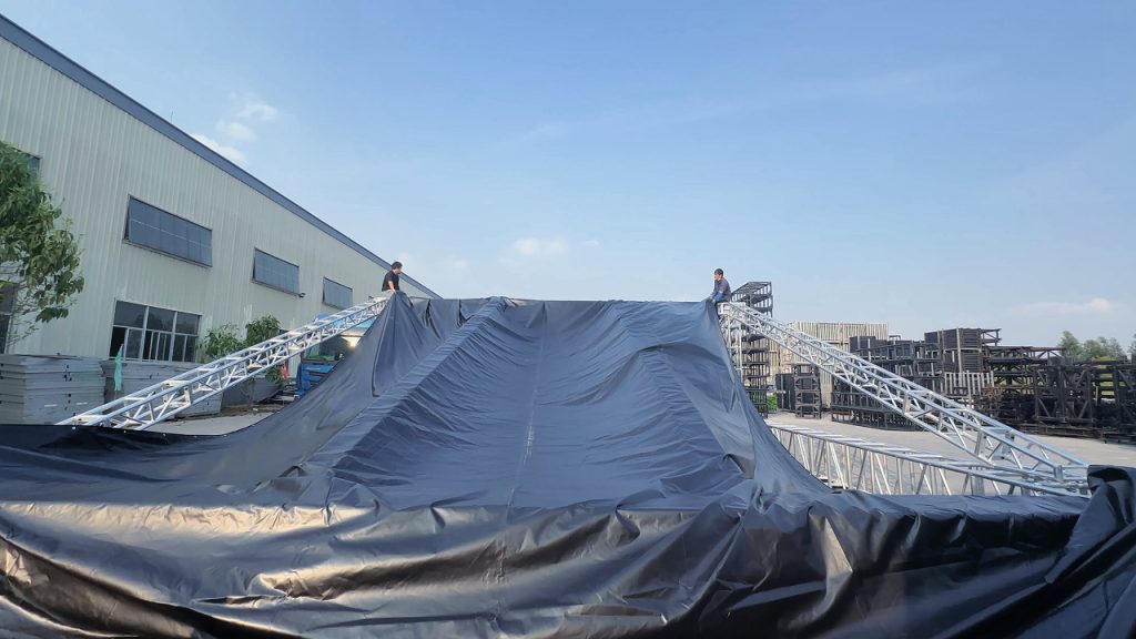Two technicians working on top of an aluminum roof truss structure during PVC roof fabric installation