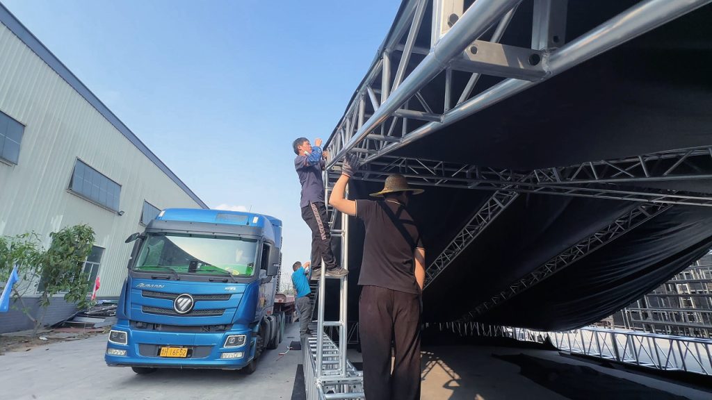 Technician securing PVC roof fabric to aluminum roof truss using cable ties during installation