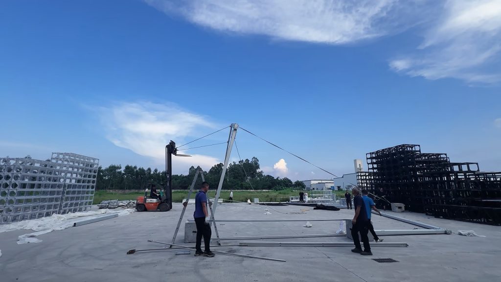 Forklift lifting the main aluminum frame during outdoor event tent installation
