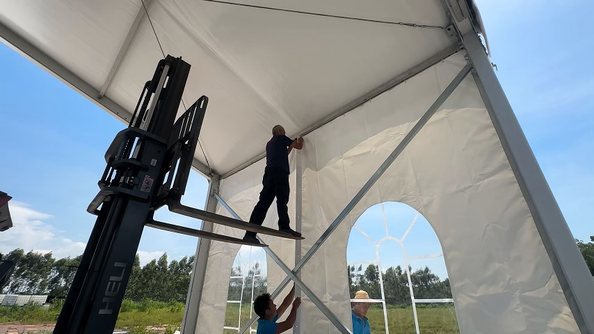 PVC sidewall installation on an aluminum outdoor event tent
