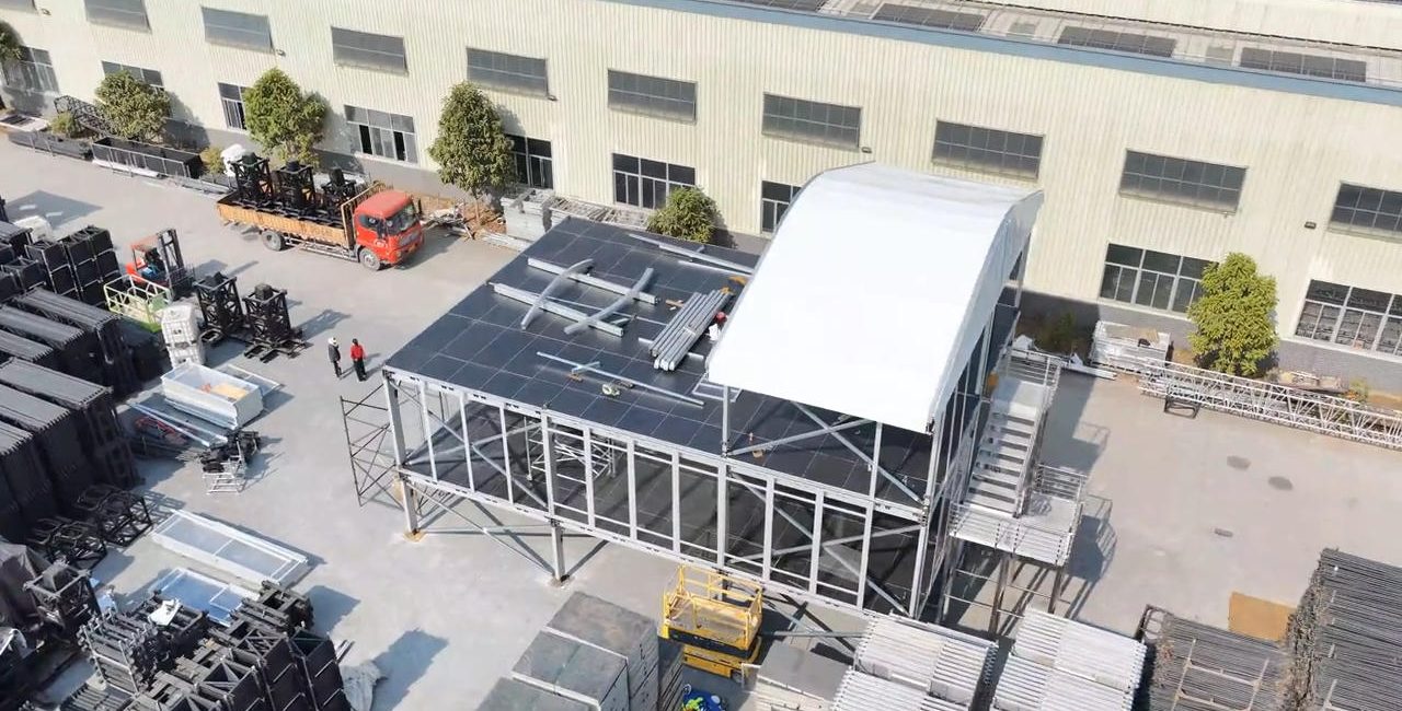 Three-tier event grandstand factory test assembly with roof canopy and stair access